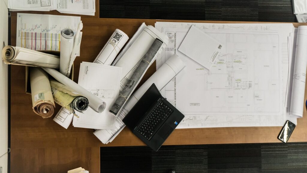 Schreibtisch mit Laptop und Bauplänen symbolisiert die Arbeit des reebuild Gründers an digitalen Lösungen für Bauunternehmen – Foto: mwitt1337 / Pixabay