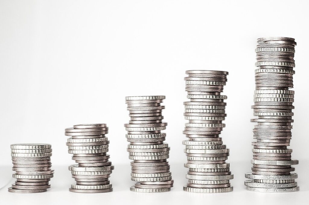 Schreibtisch mit Laptop, Münzen und Kontoauszug symbolisiert die Frage, wie viel Geld laut Finanzprofi aufs Girokonto gehört – Foto: kschneider2991 / Pixabay