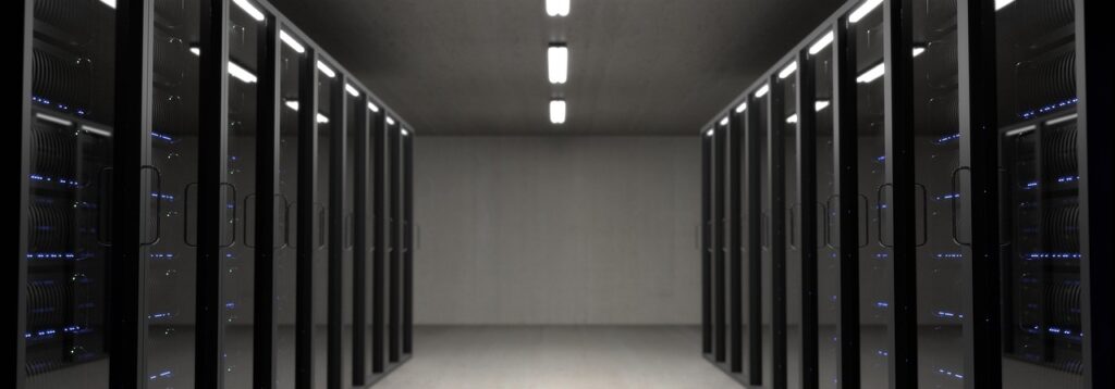 Ein leerer Rechenzentrumsgang mit beleuchteten Serverracks symbolisiert die milliardenschwere KI-Investition hinter dem Microsoft Stellenabbau – Foto: StockSnap / Pixabay