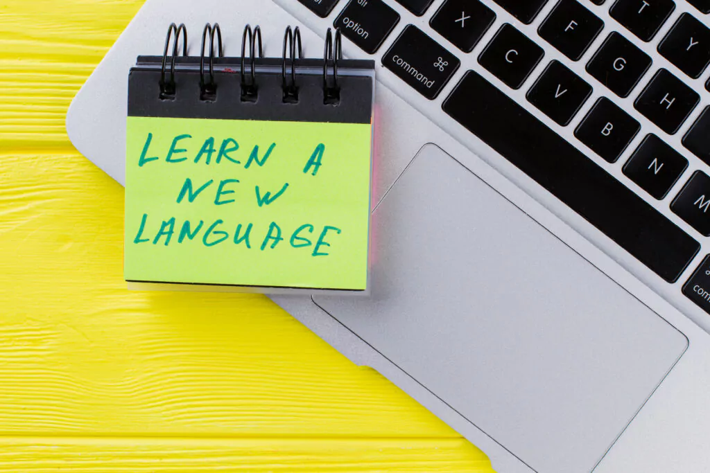 Laptop, auf dem ein Block mit der Notiz "Learn a new language" steht