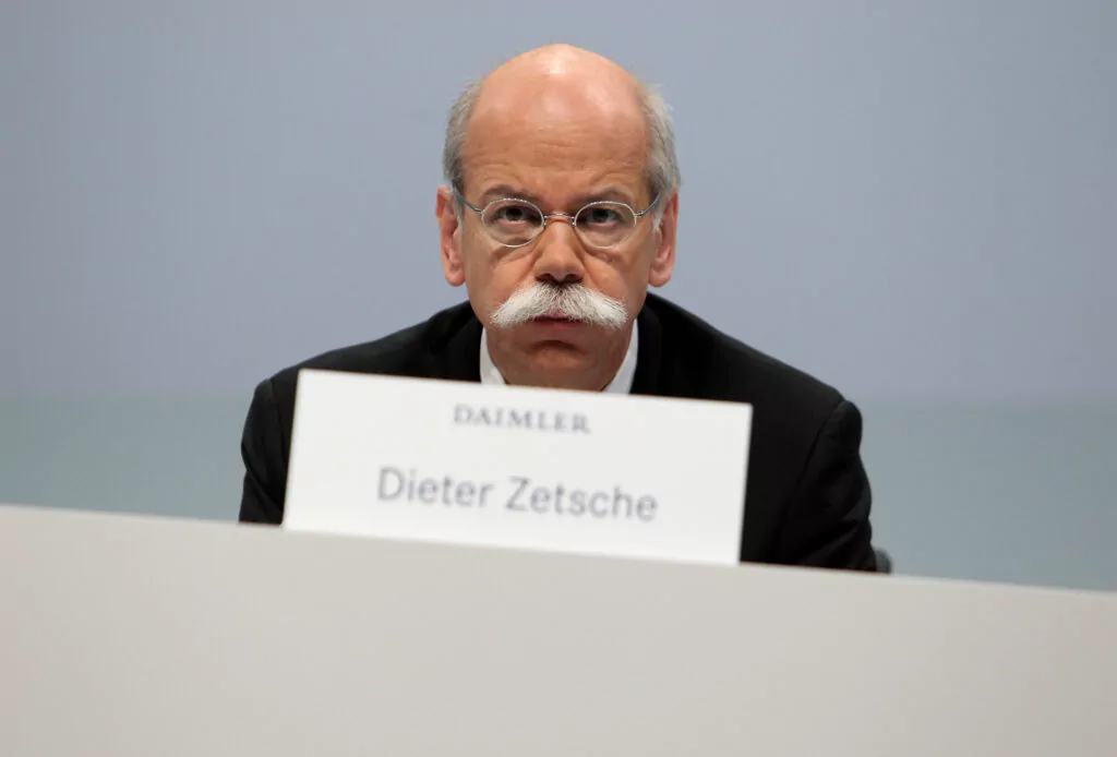 Dieter Zetsche sitzt vor dem Namenschild DAIMLER und seinem Namen darunter und blickt geradeaus